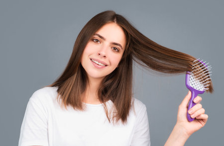 Brushing Hair. Portrait young woman brushing straight natural hair with comb. Girl combing healthy...