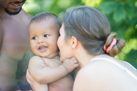 Happy multiethnic parents and amazed mixed race baby. Mixed race family outdoor portrait. Happy biracial family hug baby child. Beautiful diverse family. Multiracial family have fun together.の写真素材