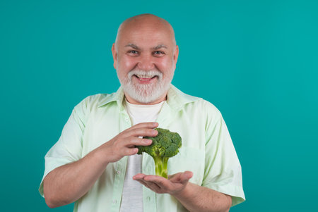 Happy Senior on Diet. Power old mature man hold broccoli. Muscular Senior man on Diet isolated in studio. Vegan senior. Mature on diet. Aged Dieting. Powerful senior. Diet for seniors.の写真素材