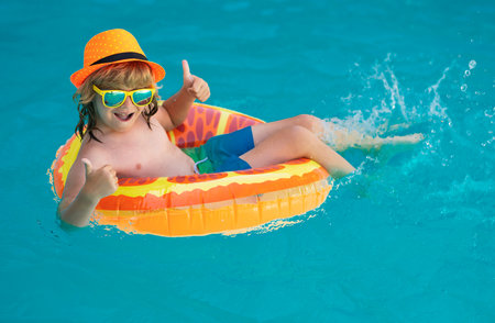 Child in swimming pool with inflatable toy ring. Children summer vacation. Swim for child on float....