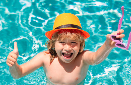 Kid boy swimming in pool play with floating ring. Smiling cute kid in sunglasses swim with inflatable rings in pool in summer day. Child relax with pool ring in beach sea water.の写真素材