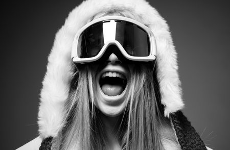 Young excited woman in ski goggles. Close up winter portrait of young amazing girl with snow goggles.の写真素材