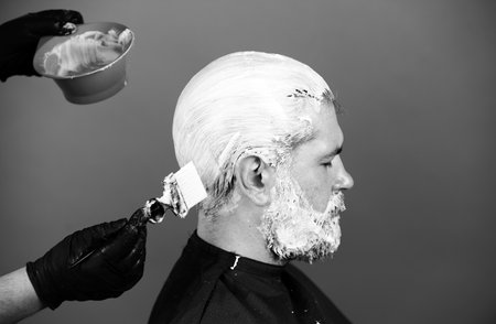 Portrait of bearded man color hair. Process of a man hair coloring at hairdresser salon.