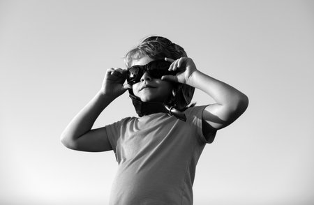 Child boy playing with pilot goggles and helmet, dream of becoming a pilot. Childrens dreams. Child pilot aviator on sky.の写真素材