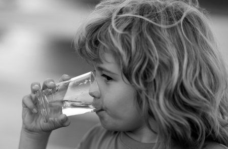 Portrait of boy drinking glass of water. Kid drinking water outdoor. Thirsty child.の写真素材