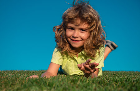 Portrait of a happy smiling child boy playing on grass field. Laughing child. Expressive facial expressions.の写真素材