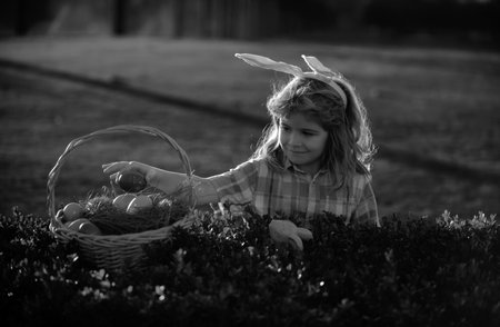 Kids boy hunting easter eggs in park. Child bunny boy with rabbit bunny ears.の写真素材