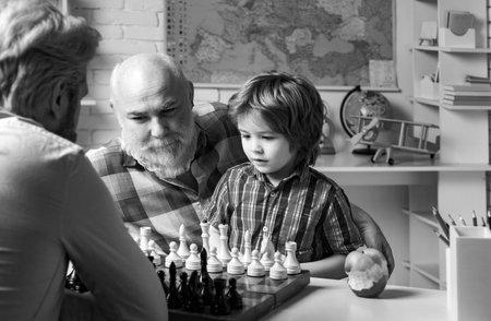 Portrait grandpa and grandson playing chess. Family relationship between grandfather father and son. Grandpa teaching school boy pupil.の写真素材