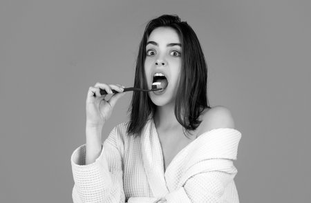 Excited amazed woman brushing teeth. Beautiful smile of young woman with healthy white teeth. Isolated background. Dental care.の写真素材