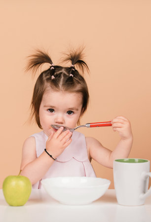 Kid eat healthy nutrition, baby food. Babies eating with spoon. Kid girl eating healthy food.の写真素材