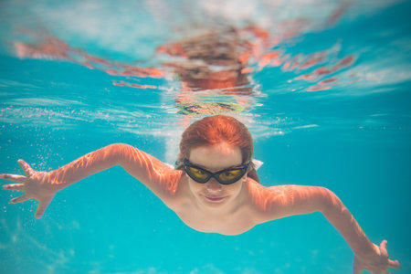 Child in swimming pool underwater. Kid underwater swim. Child splashing underwater in swimming pool. Active kids healthy lifestyle, swim underwater. Summer vacation with child. Child water game.の写真素材