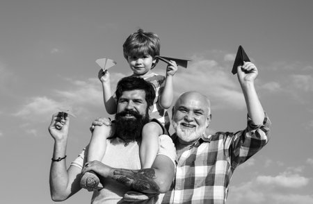 Family holiday and togetherness. Family people. Happy child playing with toy paper airplane against summer sky background. Happy fathers day.の写真素材