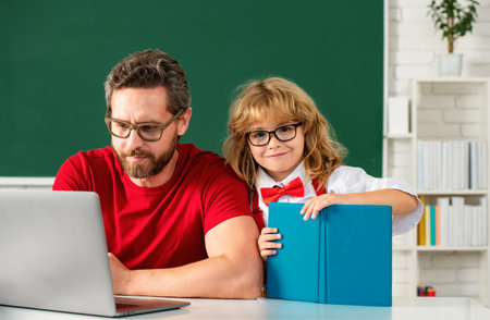 Teacher helping child student pupil from elementary school in classroom. Teacher and pupil boy...