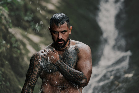 Naked sexy man at a tropical waterfall, Bali. Man relaxing with freedom. Strong fit Man in waterfall in tropical nature. Wellness spa concept in nature. Wild nature. Muscular Hispanic man posing outdoor.の写真素材