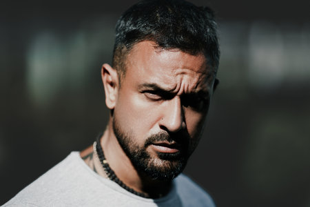 Portrait of serious man outdoor. Guy with a beard close up. Closeup face of strong man 30s having bristle looking at camera outside. Handsome sexy hispanic man. Brutal man.の写真素材