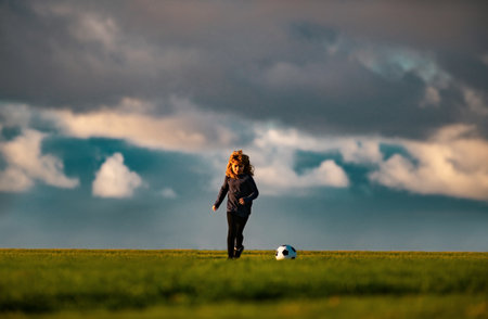 Kid playing soccer, happy child enjoying sports football game, kids activities, little soccer player. Active sporty kid soccer. Kid kicking a football ball on a grass. Training for sport children.の写真素材