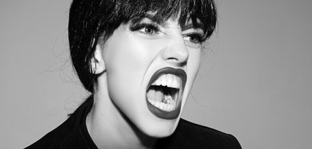 Woman shouting and screaming loud with open mouth. Human emotions, facial expression concept. Close up screaming face.の写真素材