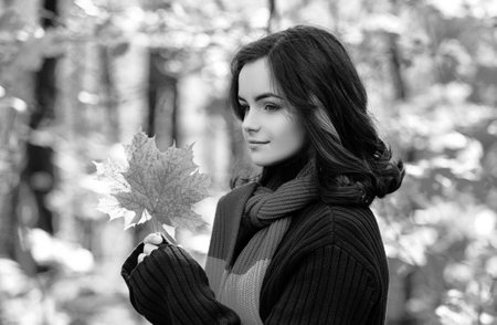 Autumn teen with red yellow leaves. Portrait of young teenage girl with autumn leafs in front of foliage.の写真素材