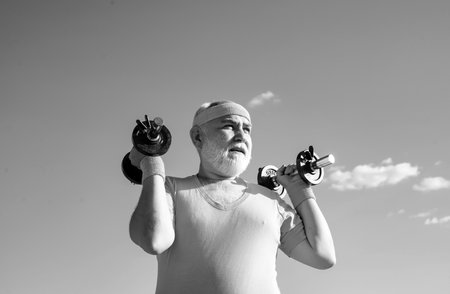 Elderly man after her workout. Healthcare cheerful lifestyle. Senior man exercising on blue sky....