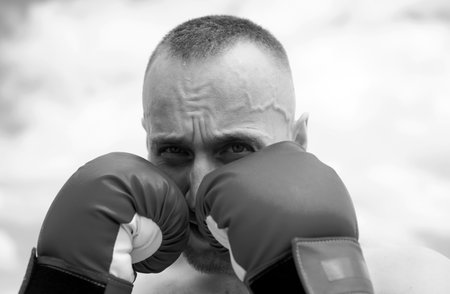 Boxer training outdoor. Closeup portrait of male boxer training defense and attacks in boxing gloves.の写真素材