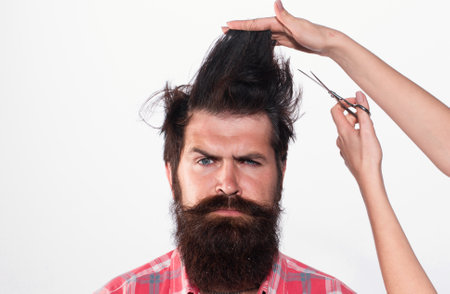 Haircut. Barber Shop procedures. Hairdresser concept. Woman cuts hair with scissors. Man with long beard, mustache and stylish hair.の写真素材