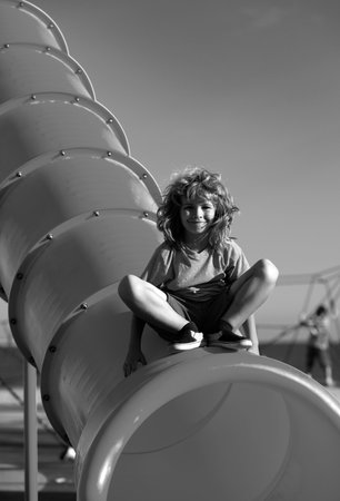 Child on slide playground area. Cute boy in the kids park having fun.の写真素材