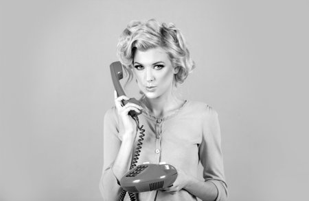 Charming girl holding phone handset, conversation on telephone. Portrait of woman with handset isolated studio background. Fashioned surprised girl talking on the phone.の写真素材