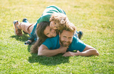Cute family portrait. Happy family mother father and child son hugging and embracing on nature. Parents and children on vacation playing together outdoor.の写真素材