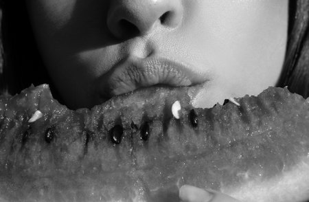 Watermelon in women mouth, close up. Girl eating, watermelon. Macro lips and atermelon. Summer fruits.の写真素材