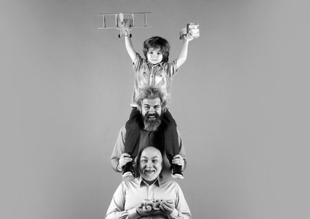 Child son with father and grandfather. Family man holiday and togetherness. Men generations. Happy child playing with toys on yellow background.の写真素材