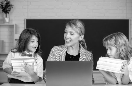 School teacher with a schoolkids learning at laptop computer, studying with online education....