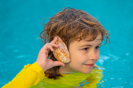 Kid listening to the ocean in a shell. Little boy holding a seashell close to his ear. Child play...