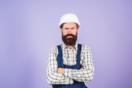 Funny bearded builder worker. Handyman builder in hardhat. Building concept. Builder foreman. Man in helmet studio portrait. Engineer worker in hardhat. Construction site manager.の写真素材