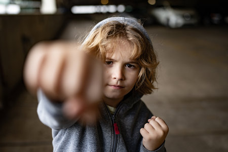 Aggressive child fight. Little kid boy fighting outside. Angry little boy showing fist. Portrait of fight kid. Bullied, physical abuse, children fighting. Aggression little boy. Kids bad behavioral.の写真素材