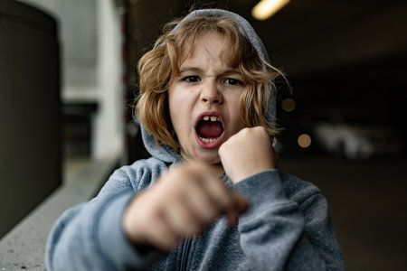 Aggressive child. Aggression kid boy fighting on street. Angry aggression kid with fist. Aggression fight kid. Bullied, physical abuse, children fighting. Aggression little boy. Kids bad behavioral.の写真素材