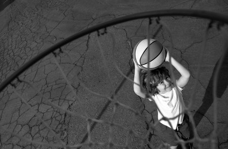 Little child boy playing basketball with basket ball. View of flying ball to basket from top, kid play basketball.の写真素材