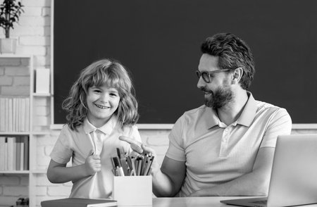 School teacher with a schoolboy. Teacher and students in the classroom. Pupil of primary elementary school has lesson. Kid boy with teacher learn english language or mathematics.の写真素材