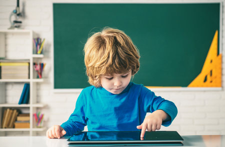 Schoolkid or preschooler learn. Education, school, technology and internet concept - little pupil with tablet pc in school.の写真素材