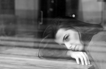 Girl in the window watching. Woman at a cafe while gazing through the window glass. Alone girl feel...
