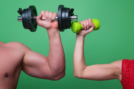 Dumbbell exercise. Male and female hands with dumbbells close-up. Training muscles. Female and male hand holds dumbbell. Muscular hands, exercises with dumbbells. Strong Dumbbell. Fitness and Sport.の写真素材