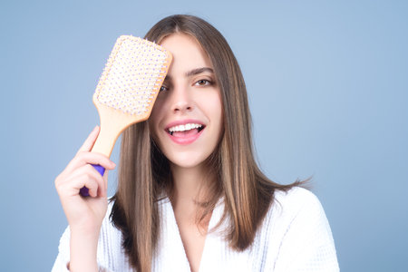 Young woman taking care with hair comb of her hair. Haircare. Pretty girl brushing hairs with comb. Beauty, hair loss products, shampoo and hair care concept.の写真素材