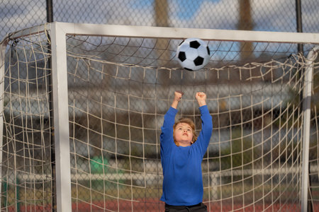 Child boy hold classic football ball in park. Kid hold football ball, banner. Kid with football ball. Sport, soccer hobby for kids. Little football player posing with soccer ball.の写真素材