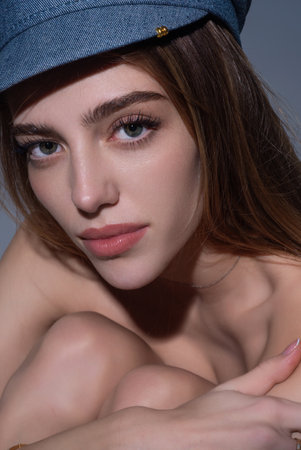 Seductive sexy lovely attractive young sensual woman with beauty face posing on studio background. Beautiful elegant sexy model with cap, studio portrait. Sensual beautiful woman face.の写真素材