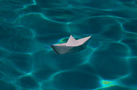 Origami ship. Cruise liner paper art. Paper boat sailing away on sea surface water background....