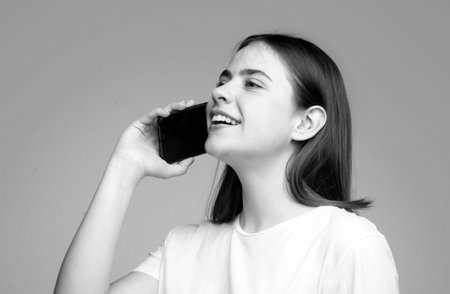 Cute beautiful young woman chatting by mobile phone isolated background. Young beautiful woman with smart phone. Phone talking.の写真素材