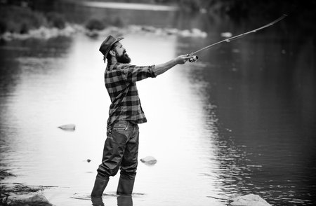 Fisherman using rod flyfishing in mountain river. A fly fisherman fishing for wild trout on the river in the forest.の写真素材