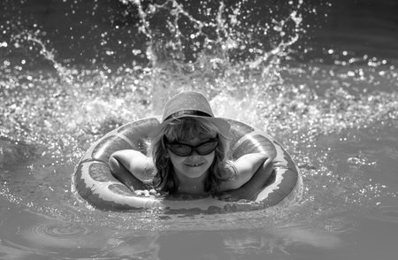 Child splashing in swimming pool. Swim water sport activity on summer vacation with child. Kids water toys.の写真素材