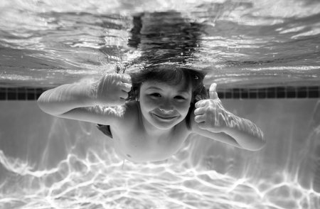 Child swim under water in sea. Kid swimming in pool underwater. Happy boy swims in sea underwater. Children in water. Summer vacation.の写真素材