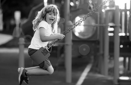 Child playing on outdoor playground. Kids play on kindergarten yard. Kid boy having fun on outdoor playground. Colorful playground with a swing, slide, climbing ladder.の写真素材