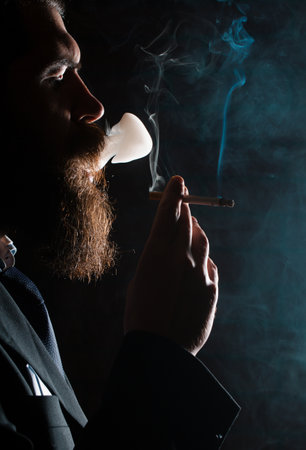 Man smoking cigarette. Cigarette smoke on black background. Smoker business man.の写真素材